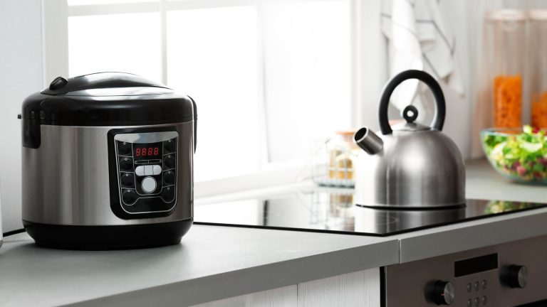 Auf einem Herd steht ein Wasserkocher, daneben ist ein Reiskocher auf der Arbeitsplatte zu sehen.