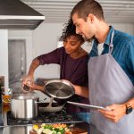 Zwei Personen stehen zusammen an einem Herd und kochen etwas.