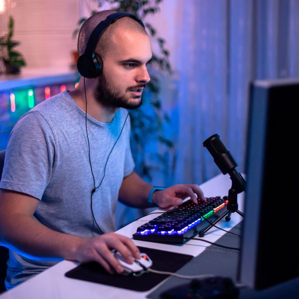 Eine Person mit einem Kopfhörer auf dem Kopf sitzt vor einem Gaming-PC und spielt etwas.