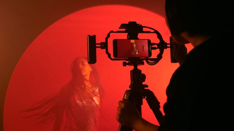 Eine Person filmt mit einem iPhone 15 Pro, das in einem Stativ steckt, eine Videosequenz.