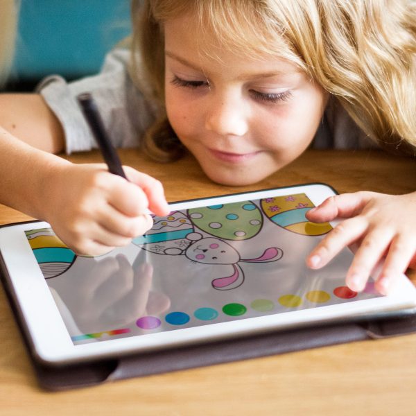 Ein Kind sitzt vor einem iPad und malt mit einem Stift darauf.