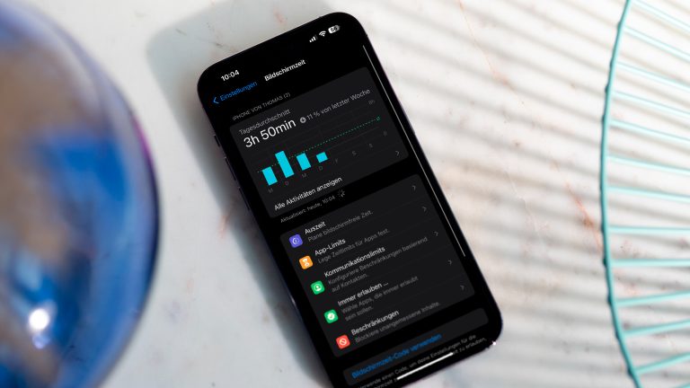 Ein iPhone liegt auf einem Tisch. Darauf ist der Screen „Bildschirmzeit“ zu sehen.