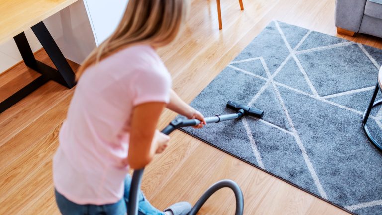 Eine Person saugt einen Teppich ab.