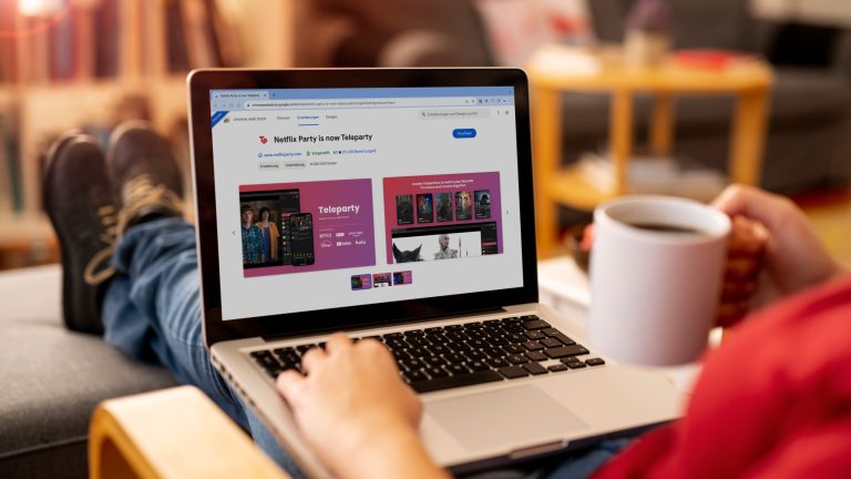 Eine Person sitzt in einem Schaukelstuhl mit einer Tasse in der Hand und einem Laptop auf dem Scho&szlig;.