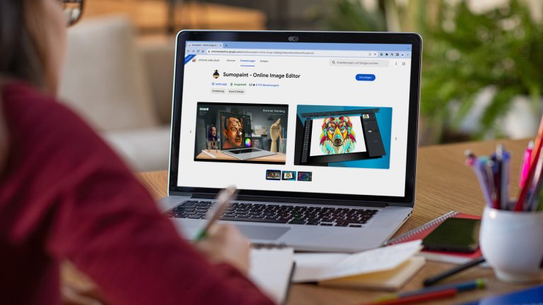 Eine Person sitzt am Schreibtisch vor einem Laptop und notiert sich etwas mit einem Stift auf einen Block. Auf dem Bildschirm ist die Google Chrome Erweiterung Sumopaint zu sehen.