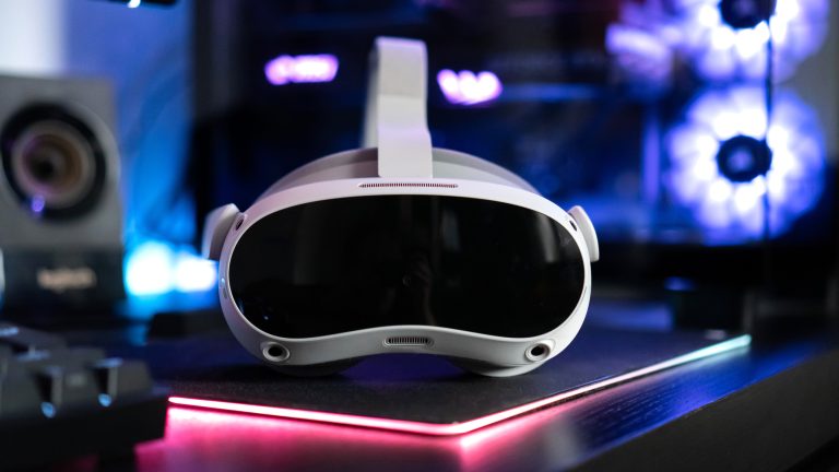 Eine Pico 4 liegt mit der Vorderseite zur Kamera vor einem Gaming-PC.