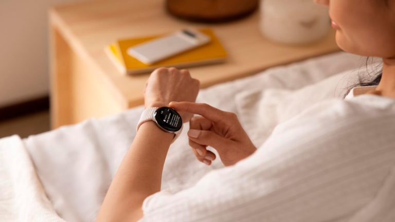 Eine Person sitzt auf einem Sofa und bedient ihre Pixel Watch 2.