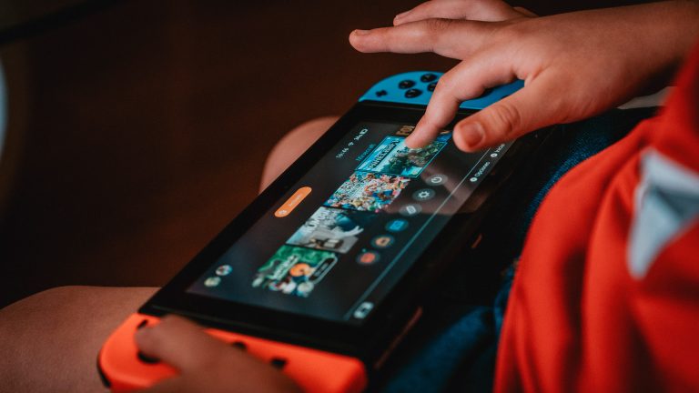 Ein Kind tippt auf einer Nintendo Switch auf ein Spiel.