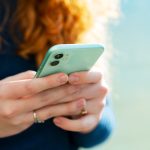 Eine Person h&auml;lt ein Smartphone in der Hand und tippt mit beiden Daumen auf das Display.