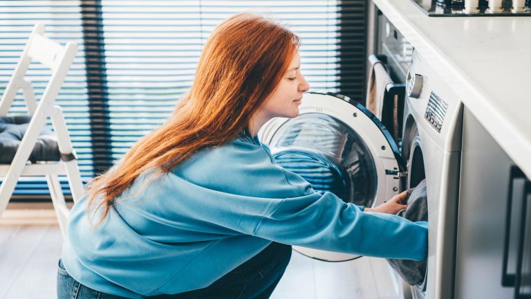 Eine Person befüllt eine Waschmaschine.