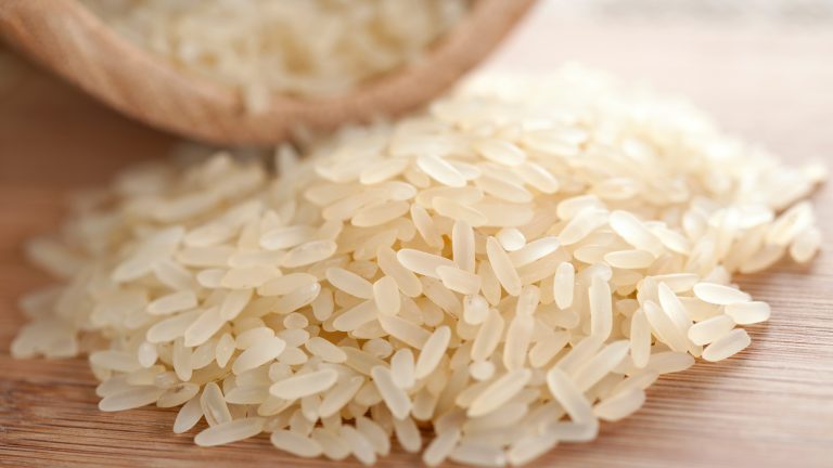 Nahaufnahme von ungekochtem Reis auf einer Holzoberfläche.