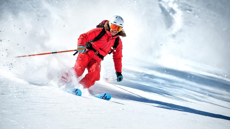 Eine Person fährt auf Skiern im Slalom eine Piste hinunter.