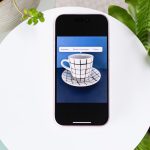 Blick auf ein iPhone, auf dem eine Tasse vor blauem Hintergrund zu sehen ist.