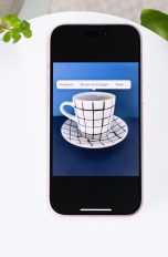 Blick auf ein iPhone, auf dem eine Tasse vor blauem Hintergrund zu sehen ist.