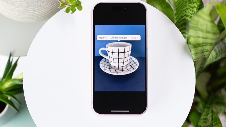 Blick auf ein iPhone, auf dem eine Tasse vor blauem Hintergrund zu sehen ist.