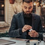 Eine Person sitzt in einem Caf&eacute; und steckt ihre AirPods wieder in das Case.