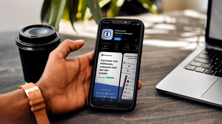 Ein Mann hält ein iPhone. Auf dem Bildschirm ist die 1Password-App im Apple App Store geöffnet.