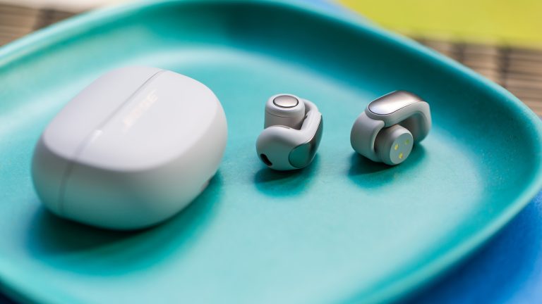 Ein Paar Ultra Open Earbuds von Bose liegt neben dem Case auf einer blauen Schale.