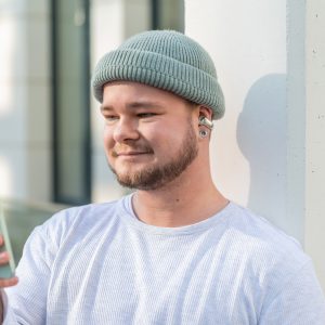 Eine Person trägt die Ultra Open Earbuds von Bose und schaut auf ein iPhone.