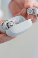 Eine Person h&auml;lt die Bose Ultra Open Earbuds in Wei&szlig; in der Hand.