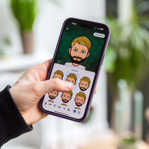Eine Person hält ein iPhone in der Hand, auf der die Bitmoji-Erstellung zu sehen ist.