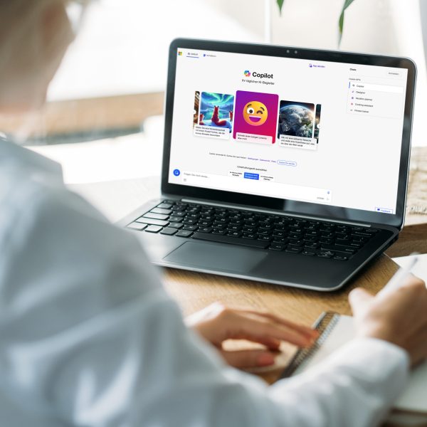 Eine Person sitzt vor einem Laptop und macht Notizen. Auf dem Bildschirm ist der Microsoft Copilot zu sehen.