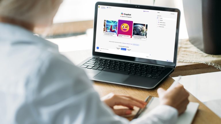 Eine Person sitzt vor einem Laptop und macht Notizen. Auf dem Bildschirm ist der Microsoft Copilot zu sehen.