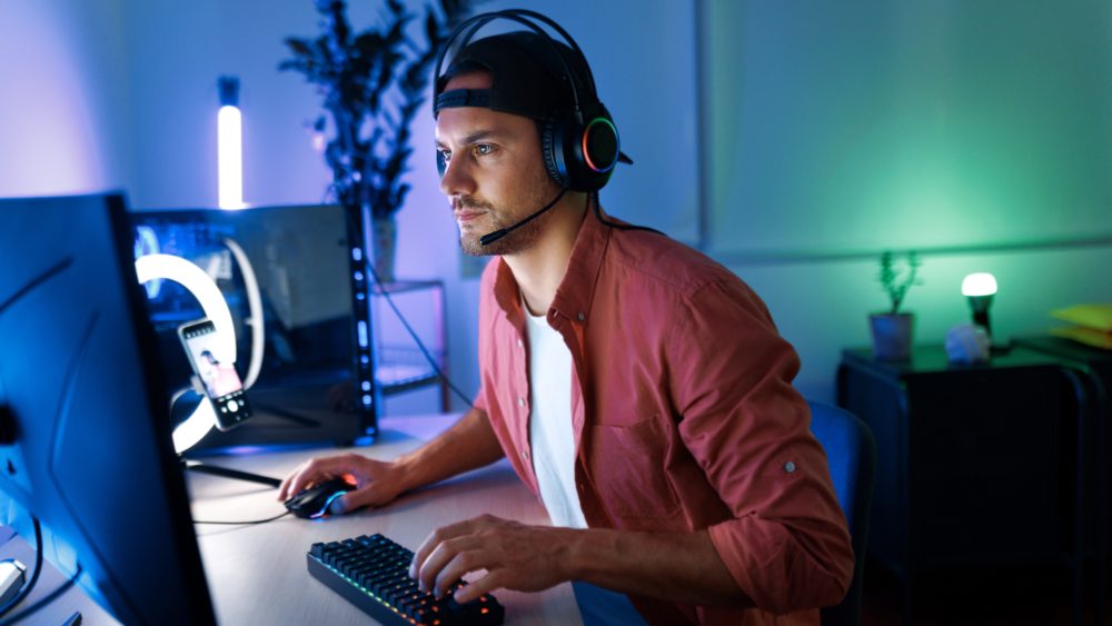 Eine Person mit einem Headset auf dem Kopf sitzt vor einem Game-Streaming-Setup.