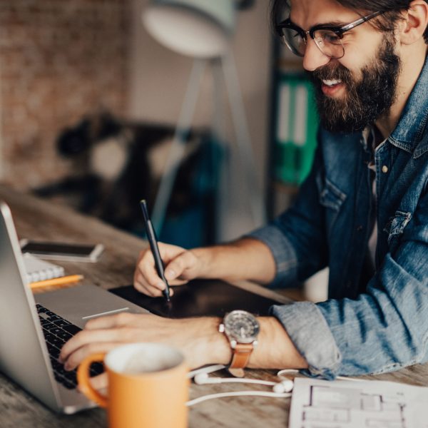 Eine Person sitzt mit einem Zeichentablet vor einem MacBook Pro.