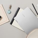 Ein gro&szlig;er Schreibtisch von oben mit diversen Gegenst&auml;nden darauf &ndash; von Laptop und Kamera, &uuml;ber Stift und Block bis hin zu Bluetooth Kopfh&ouml;rer und GPS-Tracker.