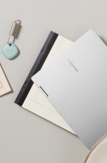 Ein großer Schreibtisch von oben mit diversen Gegenständen darauf – von Laptop und Kamera, über Stift und Block bis hin zu Bluetooth Kopfhörer und GPS-Tracker.