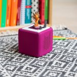 Eine pinke Toniebox steht auf einem Teppich auf dem Boden.