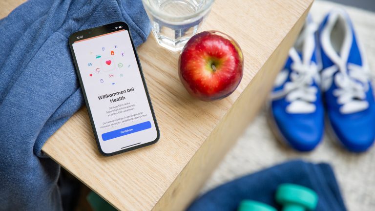 Auf einem Holztisch liegt ein iPhone. Darauf ist die Health App ge&ouml;ffnet.