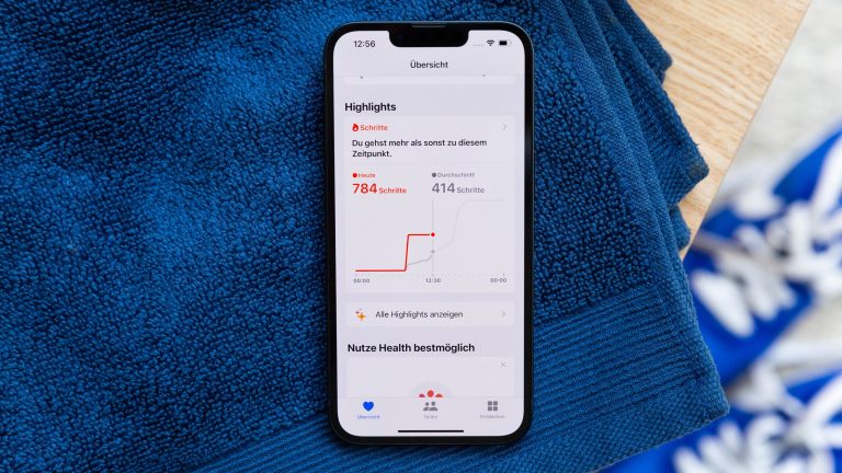 Auf einem blauen Handtuch liegt ein iPhone, darauf werden die gelaufenen Schritte als Highlight in der Health App hervorgehoben.