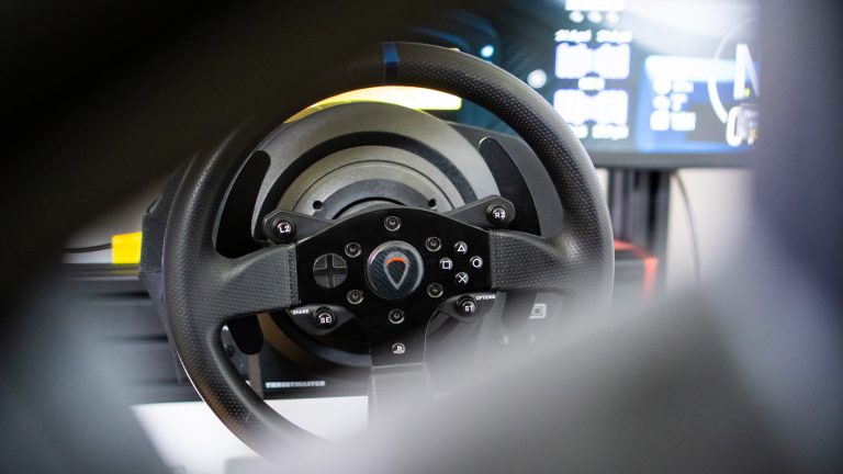 PC-Lenkräder: Das sind die drei großen Technologien Blick auf ein Thrustmaster T300 RS durch die Gurtdurchführung eines Schalensitzes.