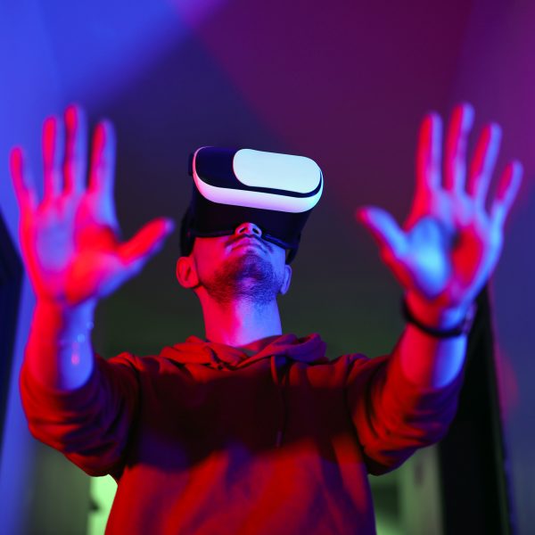 Eine Person steht mit einer VR-Brille in einem Raum und hält ihre Hände hoch.