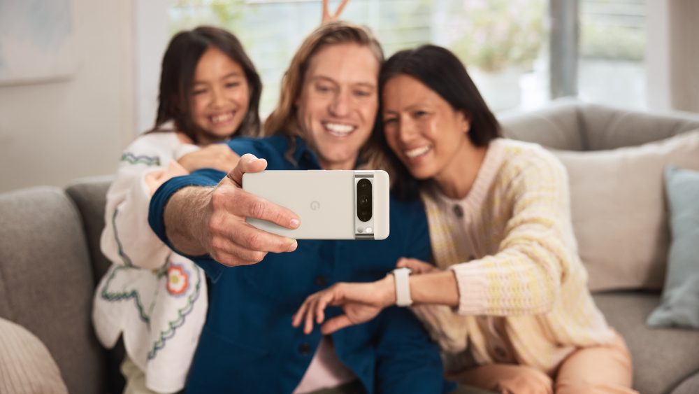 Eine Person hält ein Google Pixel in der Hand und macht ein Selfie von sich, einer weiteren Person und einem Kind.