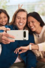 Eine Person hält ein Google Pixel in der Hand und macht ein Selfie von sich, einer weiteren Person und einem Kind.