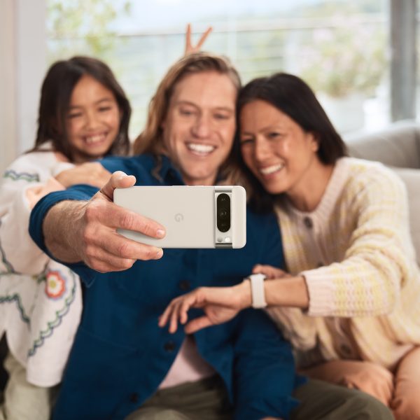 Eine Person hält ein Google Pixel in der Hand und macht ein Selfie von sich, einer weiteren Person und einem Kind.
