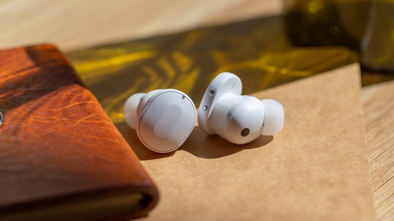 Die Fairbuds liegen nebeneinander auf einem Holztisch.
