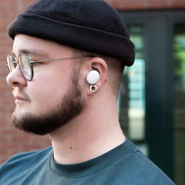 Eine Person tr&auml;gt einen wei&szlig;en In-Ear-Kopfh&ouml;rer von Fairphone.