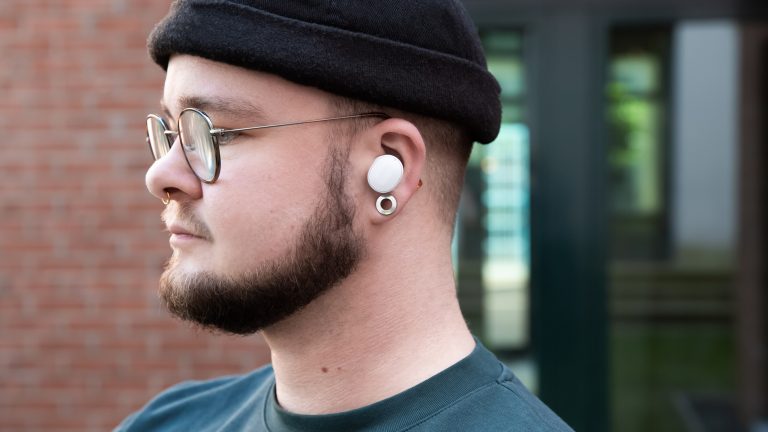 Eine Person tr&auml;gt einen wei&szlig;en In-Ear-Kopfh&ouml;rer von Fairphone.