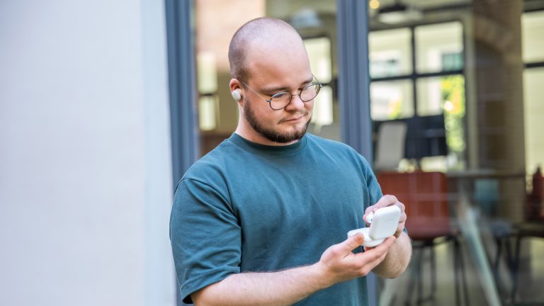 Eine Person tr&auml;gt einen Fairbud im Ohr und nimmt den zweiten aus dem Ladecase.
