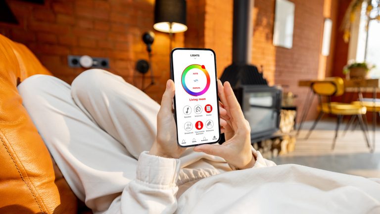 Eine Person h&auml;lt ein Smartphone in der Hand, auf der die App-Steuerung von smarter Beleuchtung zu sehen ist.