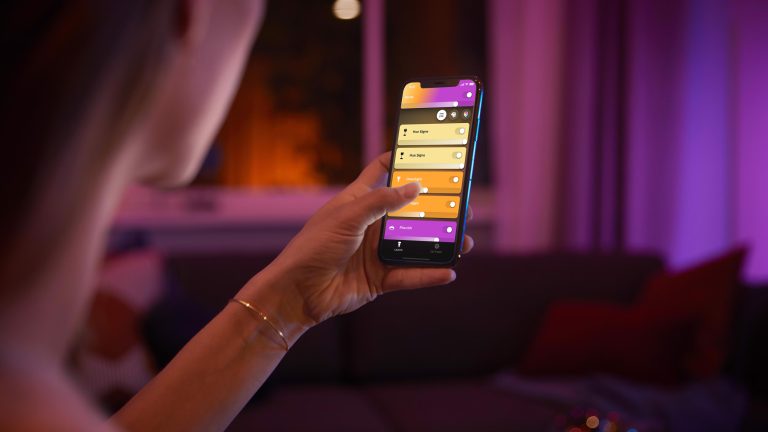 Eine Person hält ein Smartphone in der Hand. Darauf läuft die Hue-App.