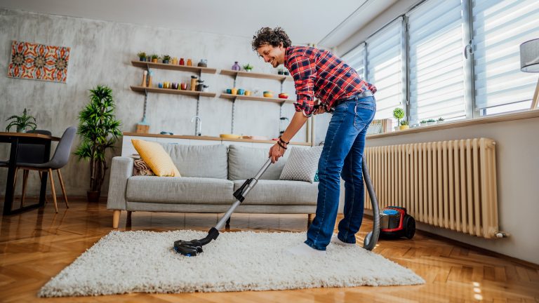 Eine Person saugt in ihrem Wohnzimmer den Teppich.