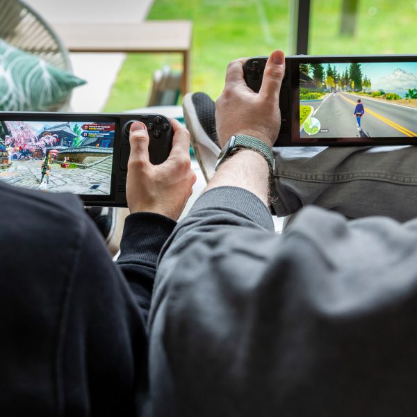 Zwei Personen sitzen nebeneinander und spielen auf einem Steam Deck OLED und Steam Deck LCD.