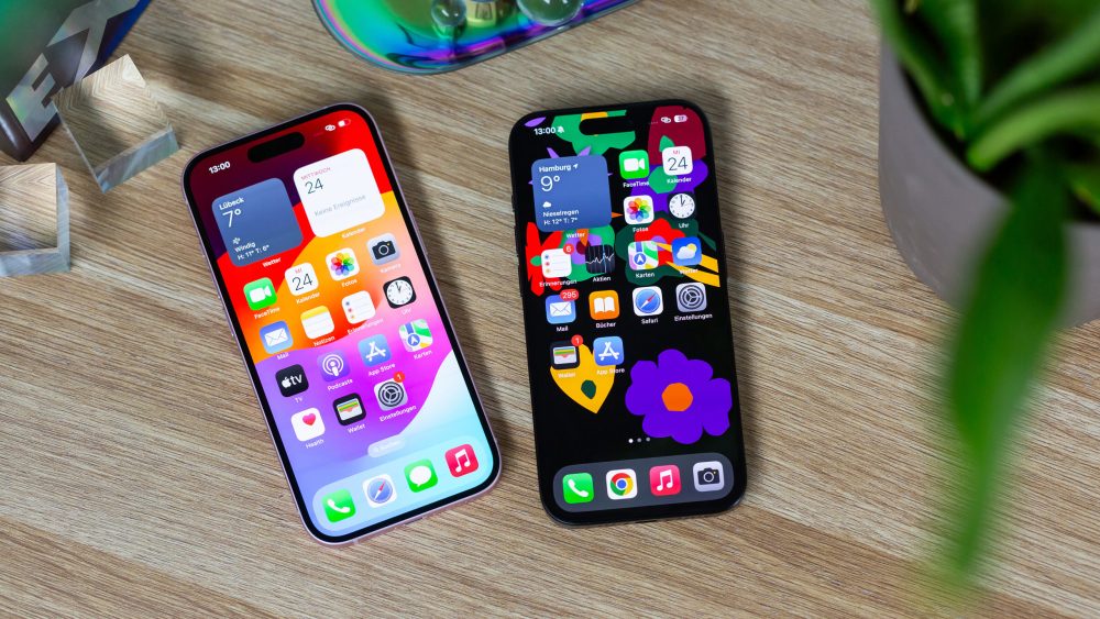 Auf einem Holztisch liegen ein iPhone 15 Pro und ein iPhone 15 nebeneinander. Auf dem eingeschalteten Display ist die Dynamic Island bei beiden Geräten zu erkennen.