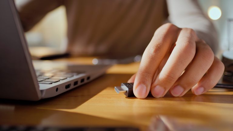 Eine Person steckt ein Ladekabel seitlich in einen Laptop. Man sieht die verschiedenen Anschl&uuml;sse.