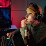 Eine Person mit Headset auf dem Kopf sitzt vor einem Gaming-Rechner.